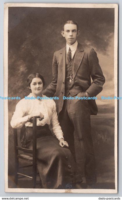 R757684 Woman sitting on the Chair near Standing Man in a Suit G H Greenwood